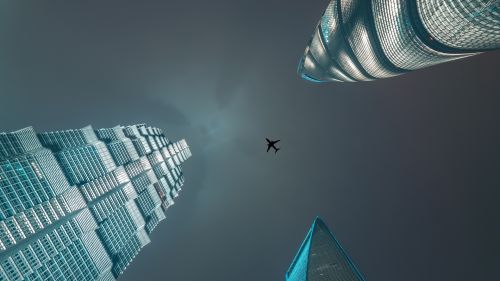 Plane flying over skyscrapers HD Wallpaper