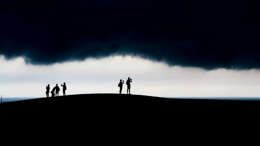 People under dark clouds HD Wallpaper